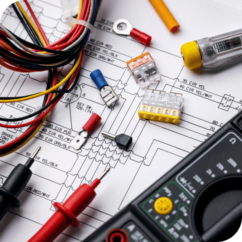 Electrical testing equipment, parts, and wires laid over a circuit diagram